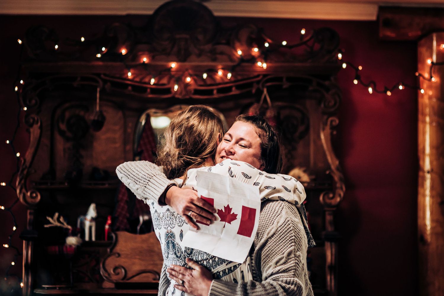 Joyful embrace at wedding celebration with string lights creating warm atmosphere.