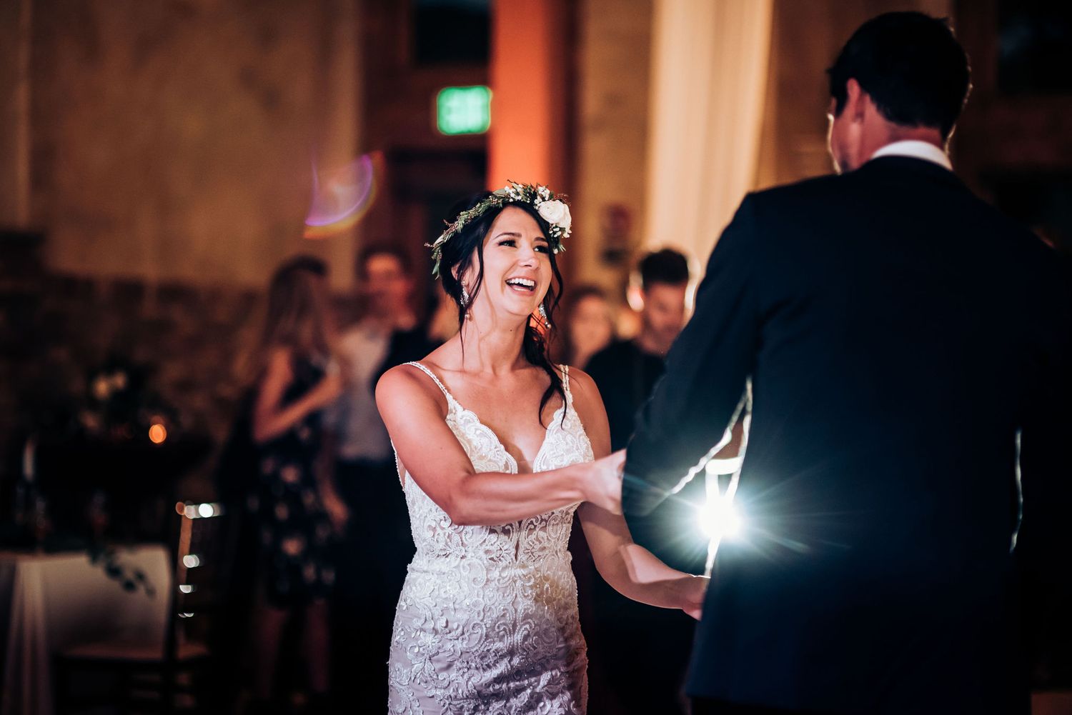 A bride in a white lace gown dances with her partner at an elegant wedding reception.
