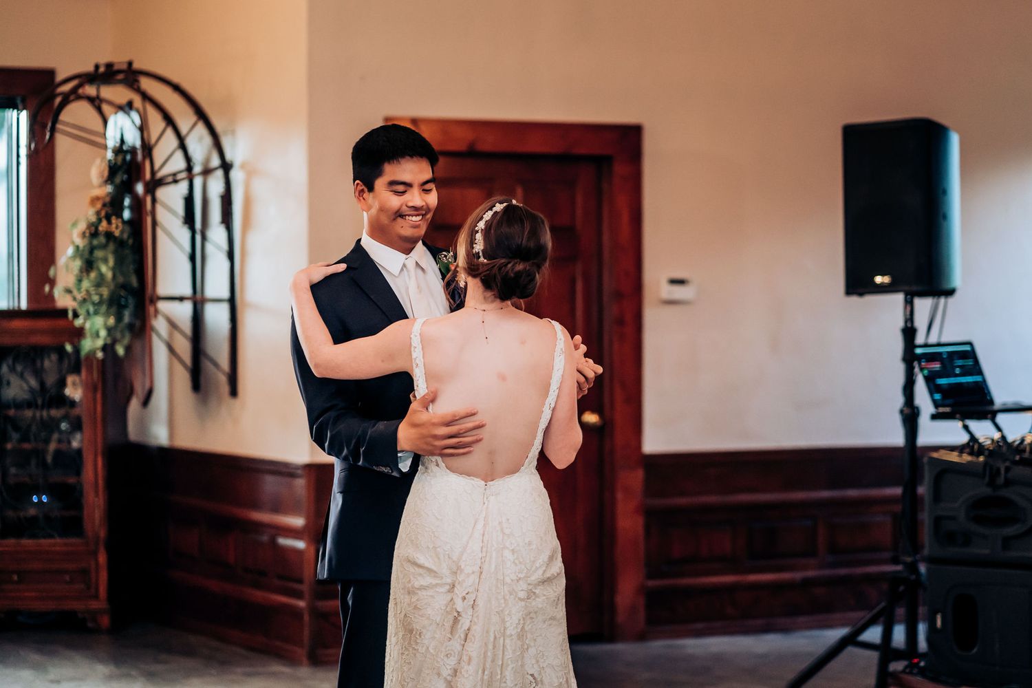 A couple sharing their first dance in an elegant reception venue with wooden decor.
