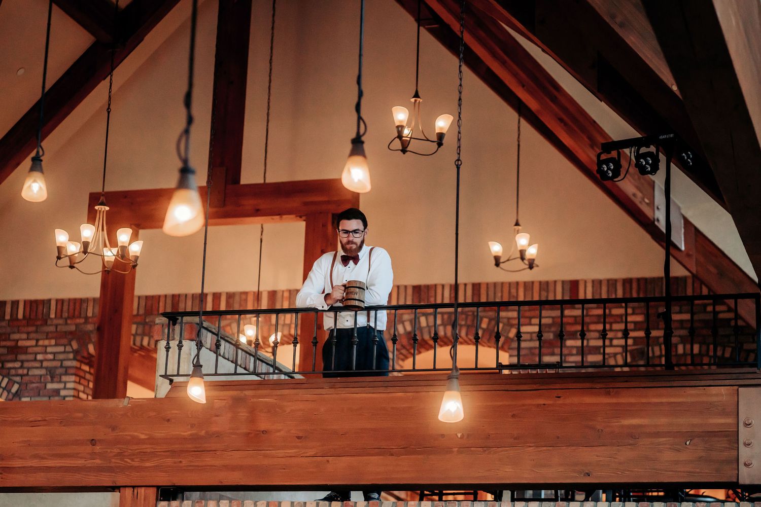 A view of a rustic indoor venue with wooden beams and hanging pendant lights.