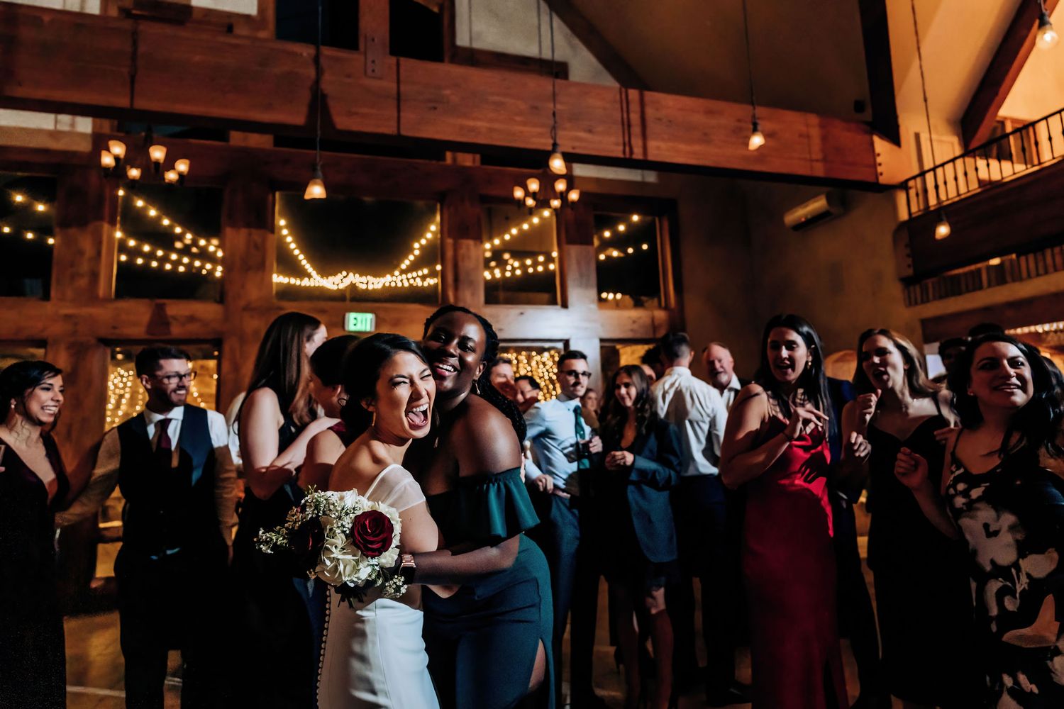 Wedding celebration in a rustic venue with string lights and exposed wooden beams.