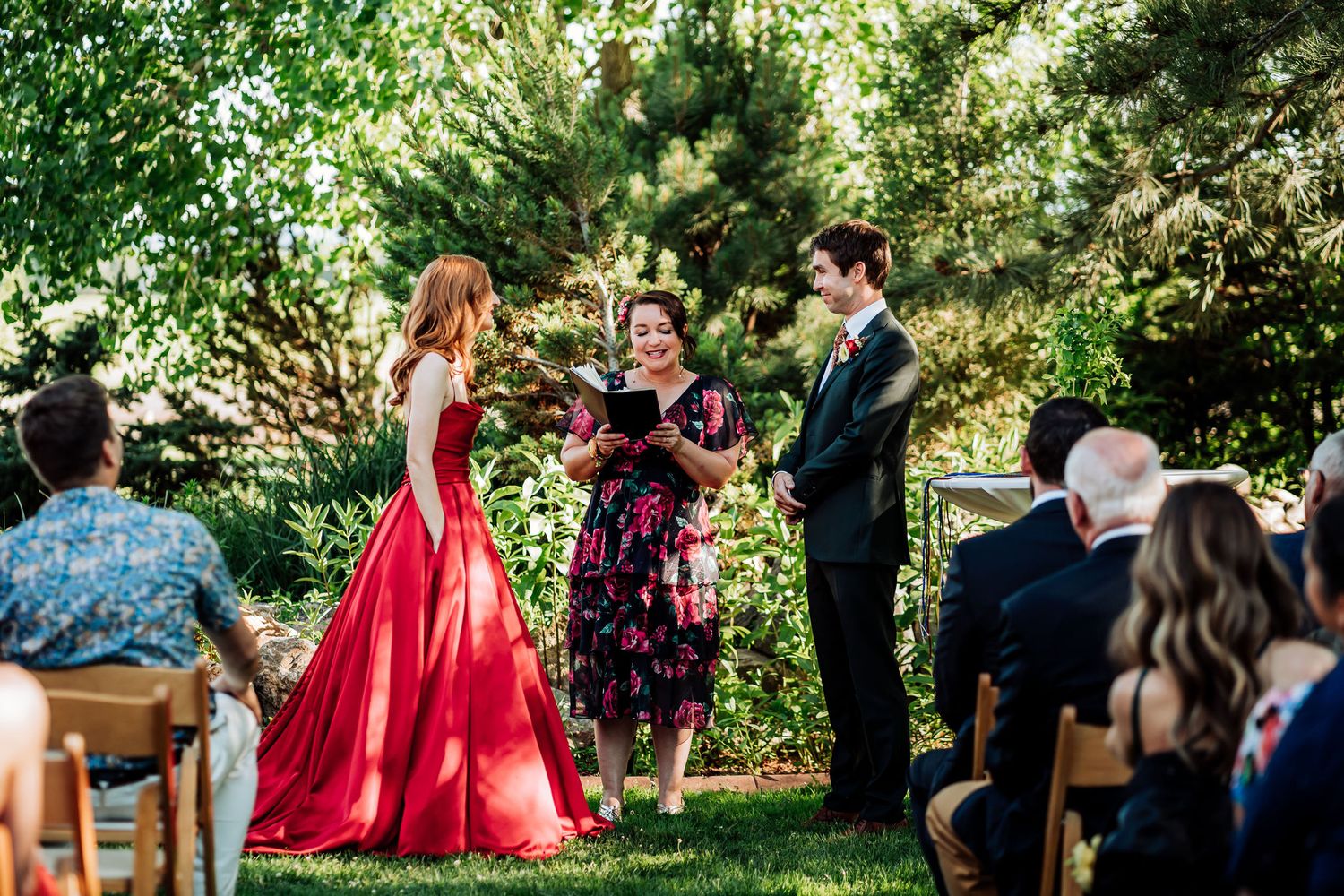 Outdoor wedding ceremony taking place in a lush garden setting with guests seated.