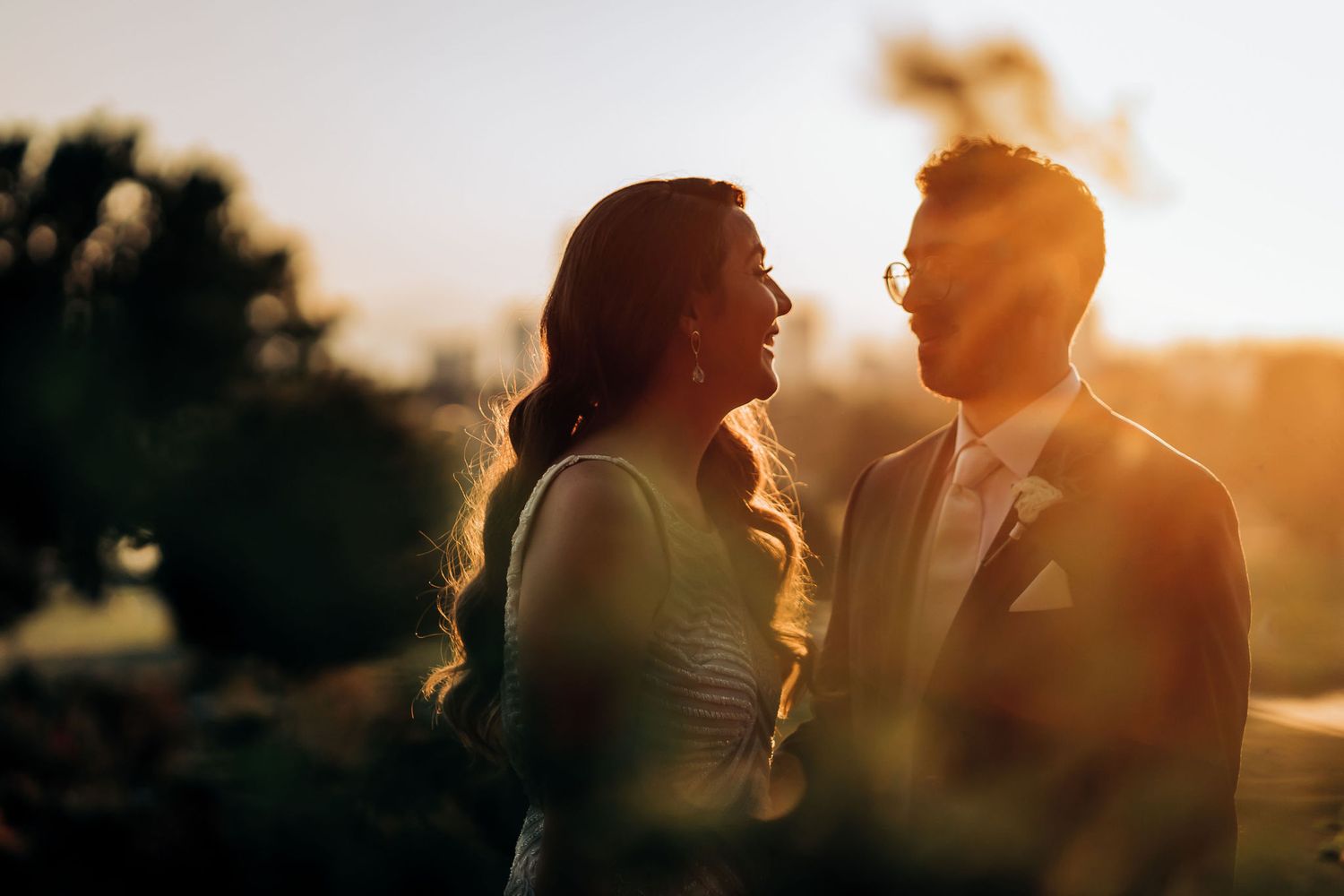 Silhouetted couple sharing an intimate moment at sunset in a romantic outdoor setting.