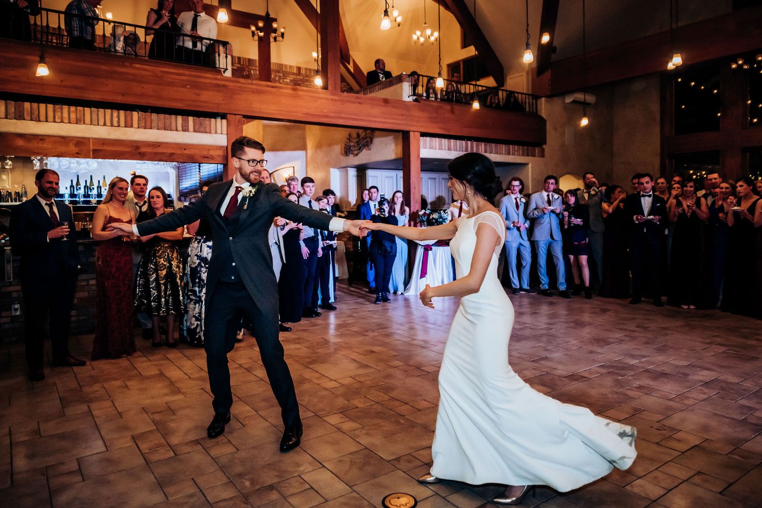 A couple dances playfully during their wedding reception in a beautifully lit ballroom.