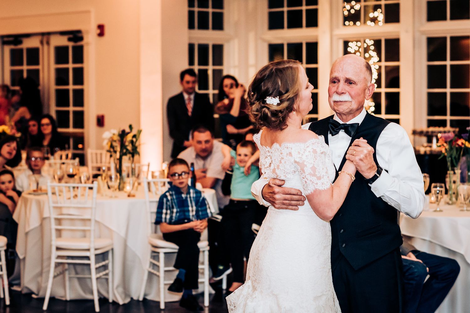Couple dances together during wedding reception while guests look on.