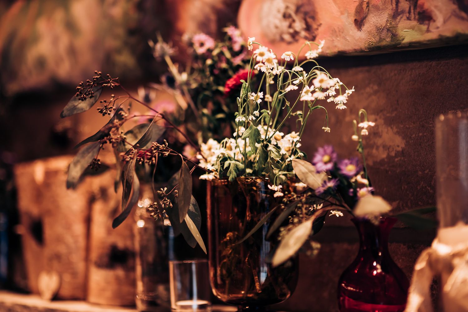 Moody floral arrangement with white flowers in dark glass vases.