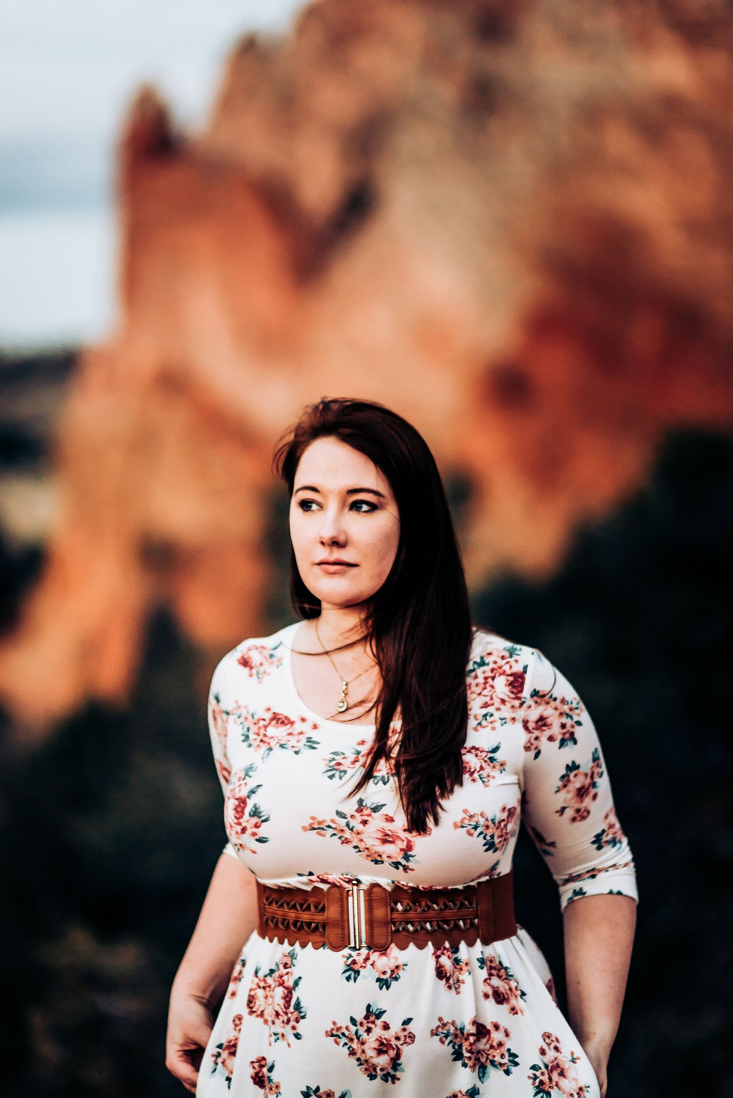 Woman in floral dress with brown belt poses against red rock formations at Garden of the Gods.