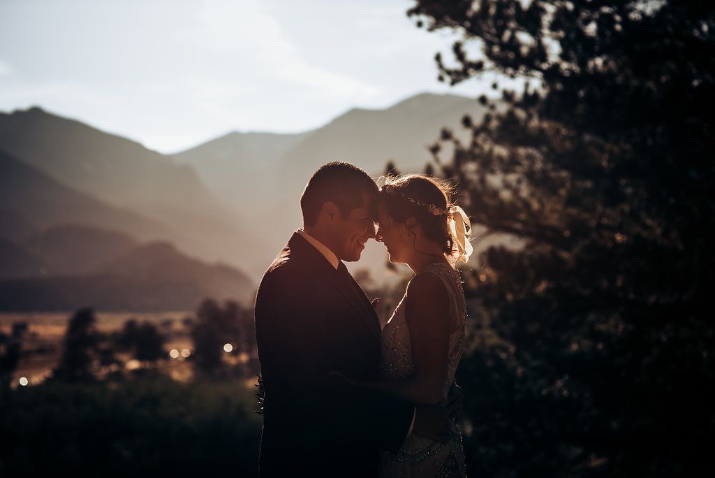 A romantic silhouette against mountain landscape during golden sunset light.