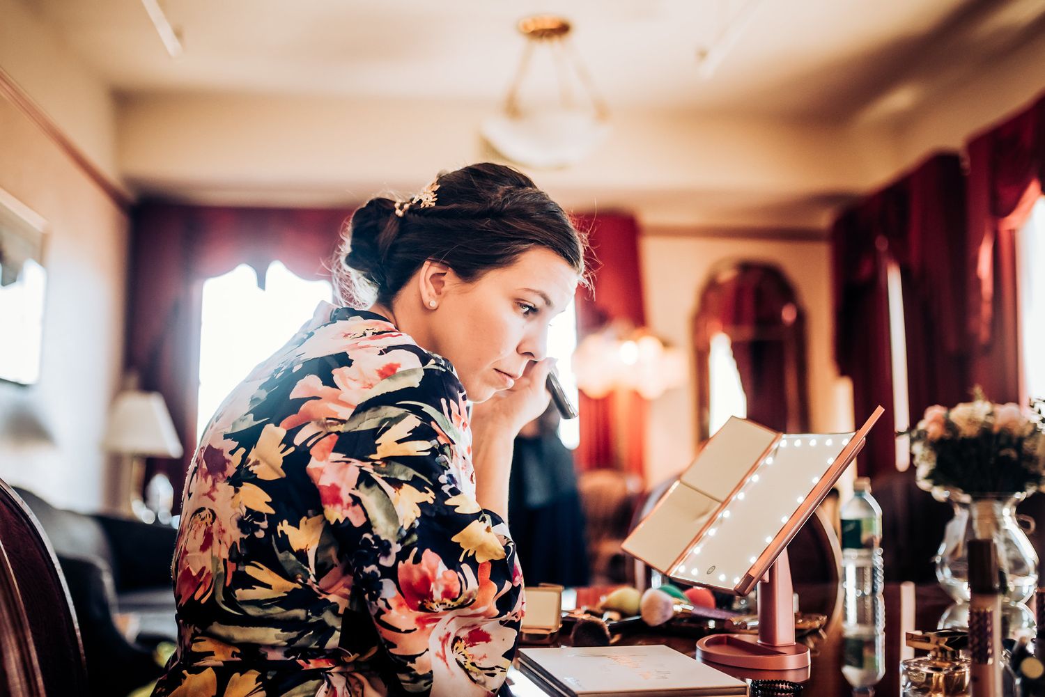 A person in a floral robe reads intently while seated at an elegant table.