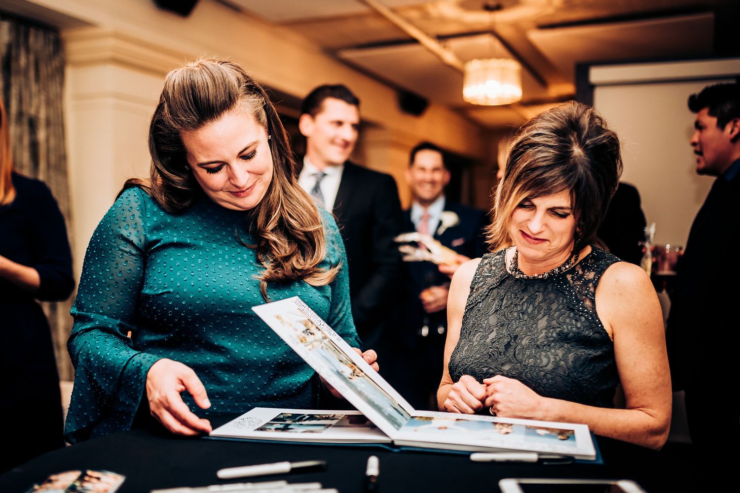 Two women looking through a photo album or guestbook at an event.