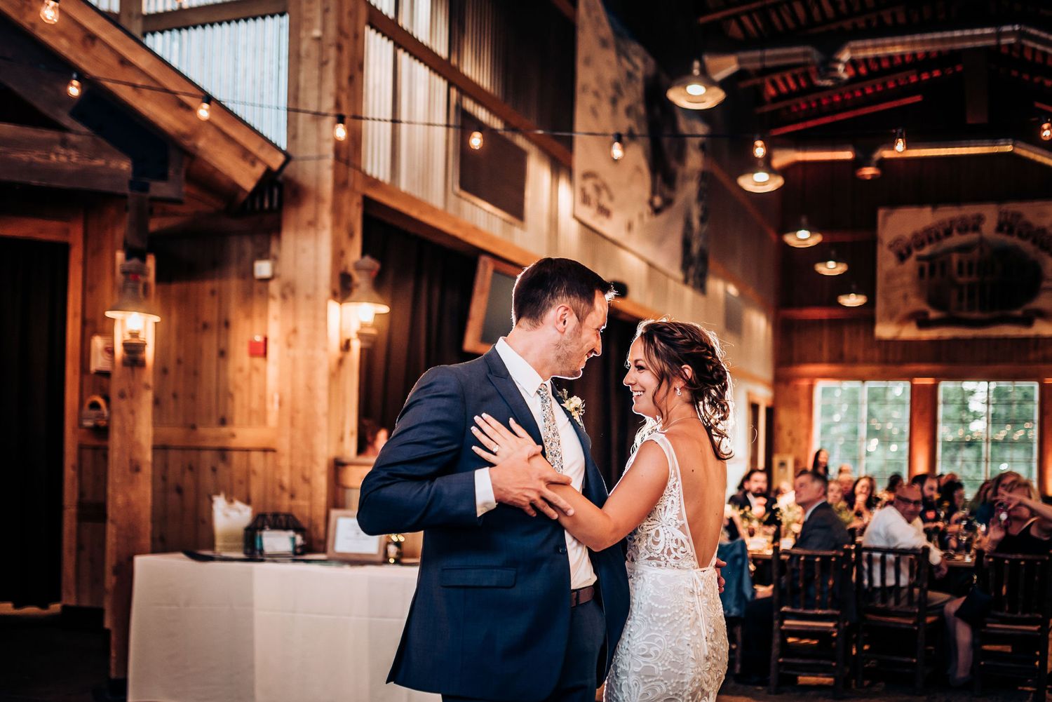 Newlyweds share an intimate moment during their first dance in a rustic barn reception venue.