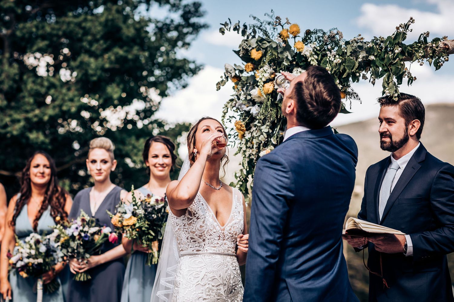 Emotional moment during outdoor wedding ceremony with bridesmaids in blue dresses.