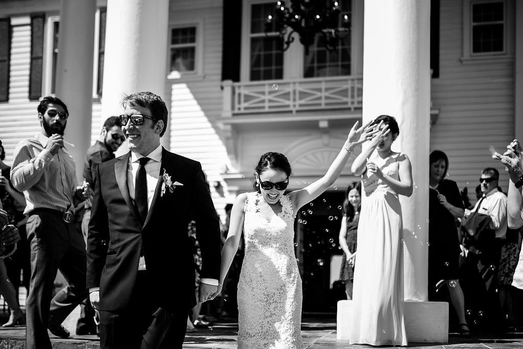 Black and white photo of wedding party celebrating outside columned building.
