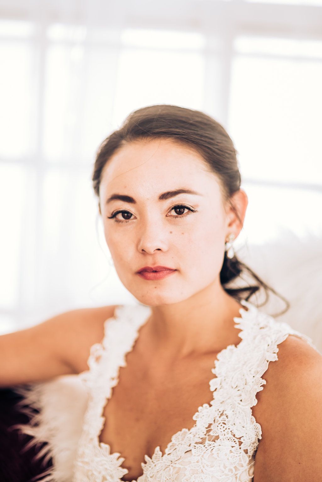 Bride in lace dress poses for portrait in bright natural lighting.