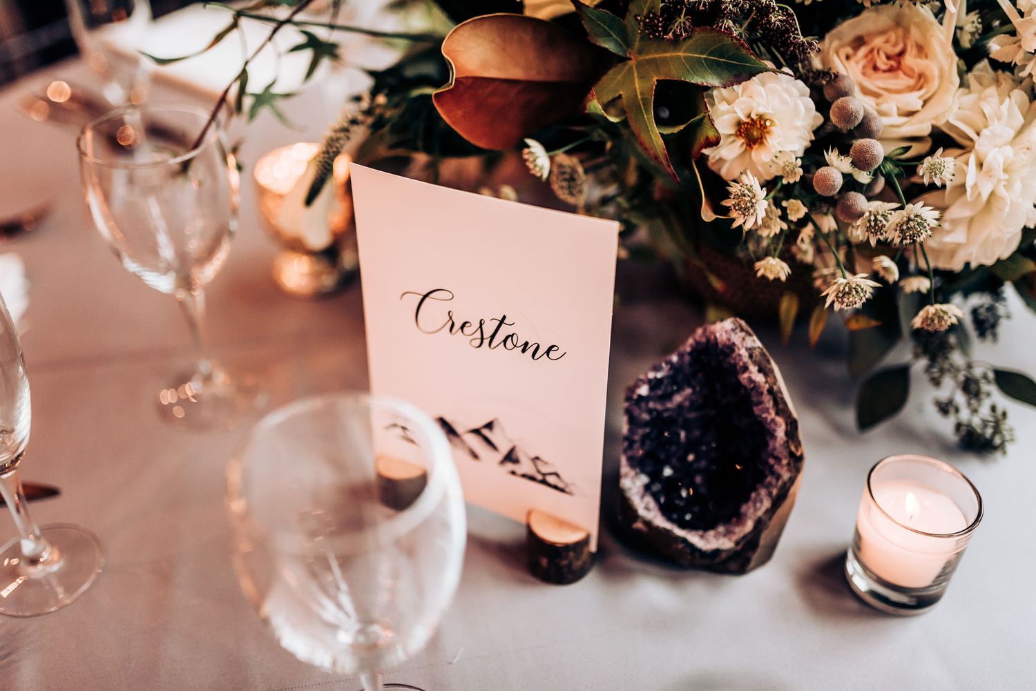 Wedding table centerpiece with crystals, name cards, and soft floral arrangements.