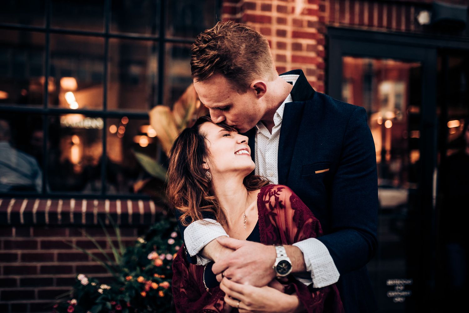 Intimate moment captured between couple against evening urban setting.