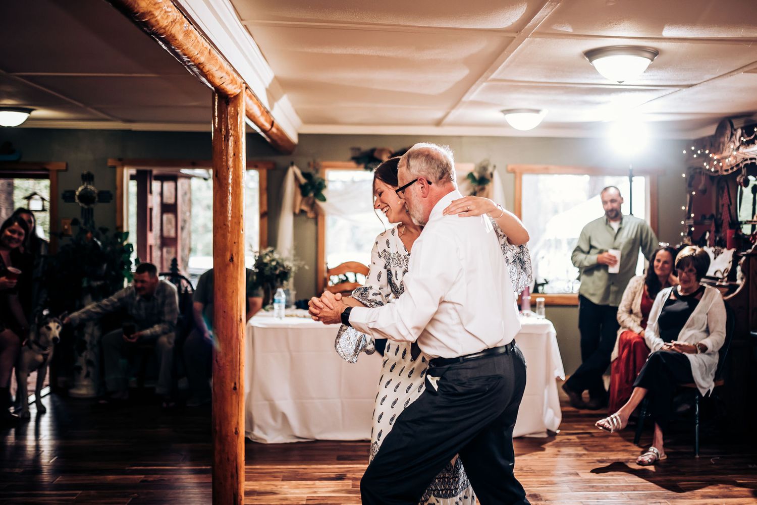 Dancing partners share a lively moment on the reception dance floor surrounded by guests.