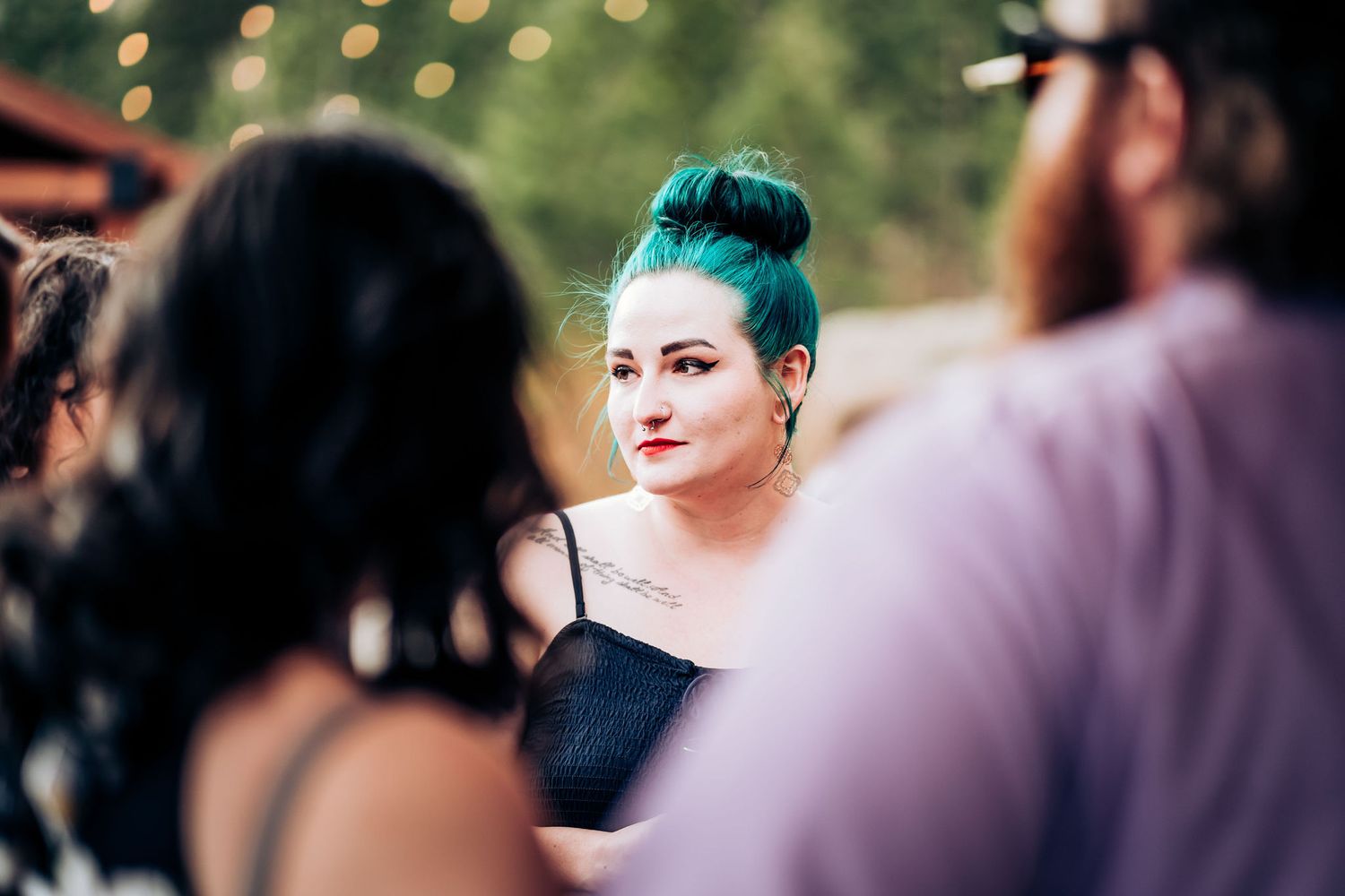 A guest with teal hair attends an outdoor wedding reception.