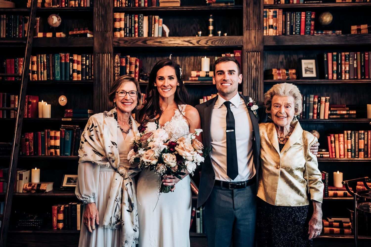 Formal wedding portrait in front of floor-to-ceiling library bookshelves.