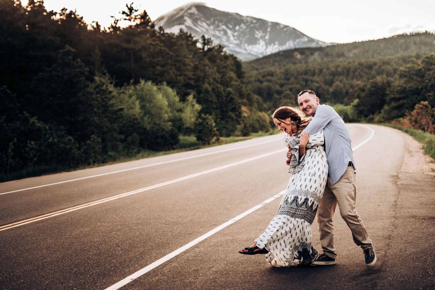 Couple playing and dancing together on empty mountain highway.