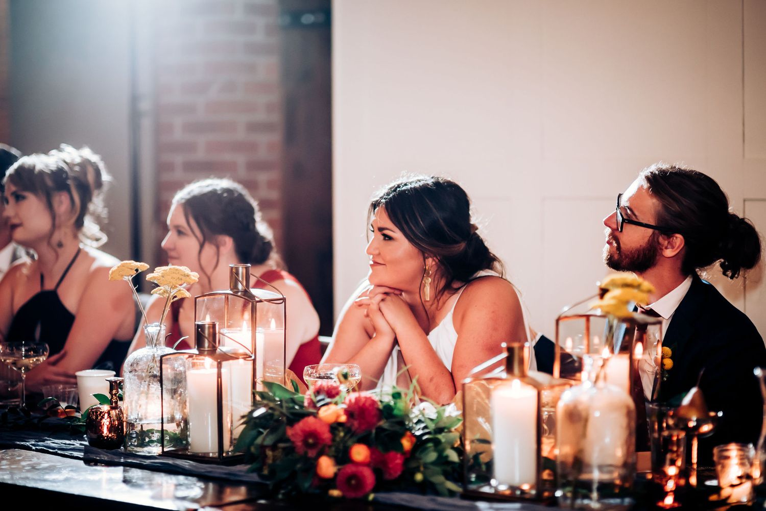 Elegant dinner party guests seated at a decorated table with candlelight and floral arrangements.