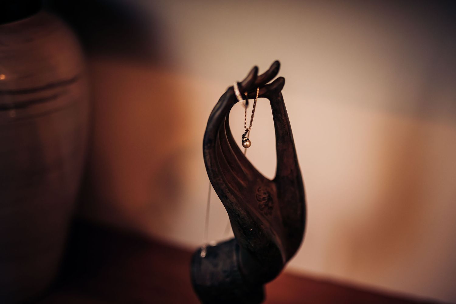 Close-up of a hand holding wedding rings in dark moody lighting.