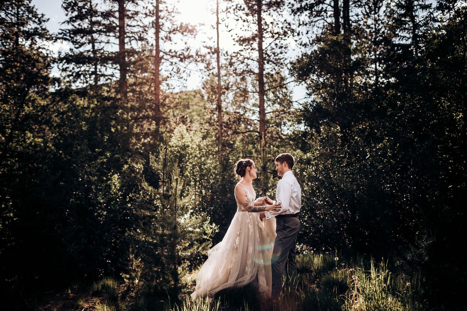 An intimate forest wedding portrait with soft natural lighting filtering through pine trees.