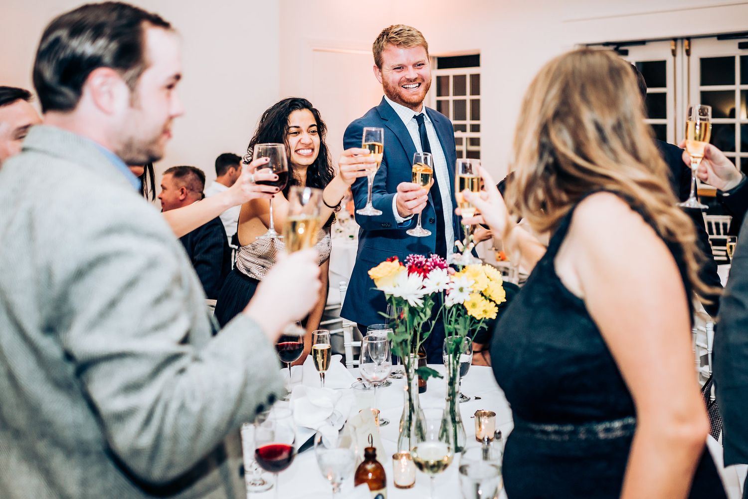 Wedding guests raise glasses for a celebratory toast during reception dinner.
