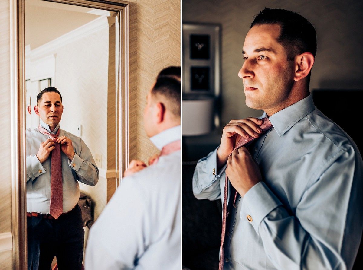 A person adjusts their tie while looking in a mirror during formal preparations.