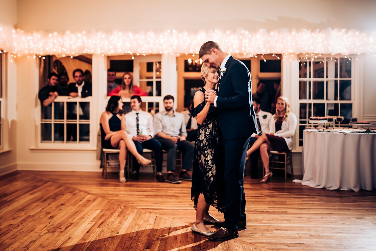 Couples dancing together at an elegant reception venue decorated with string lights.