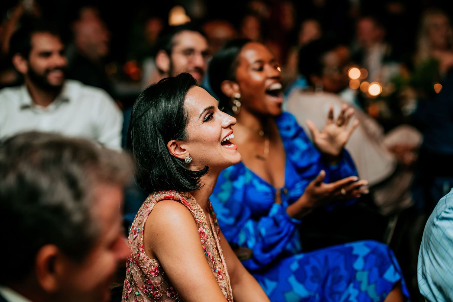 Audience members laugh enthusiastically during a live entertainment performance.