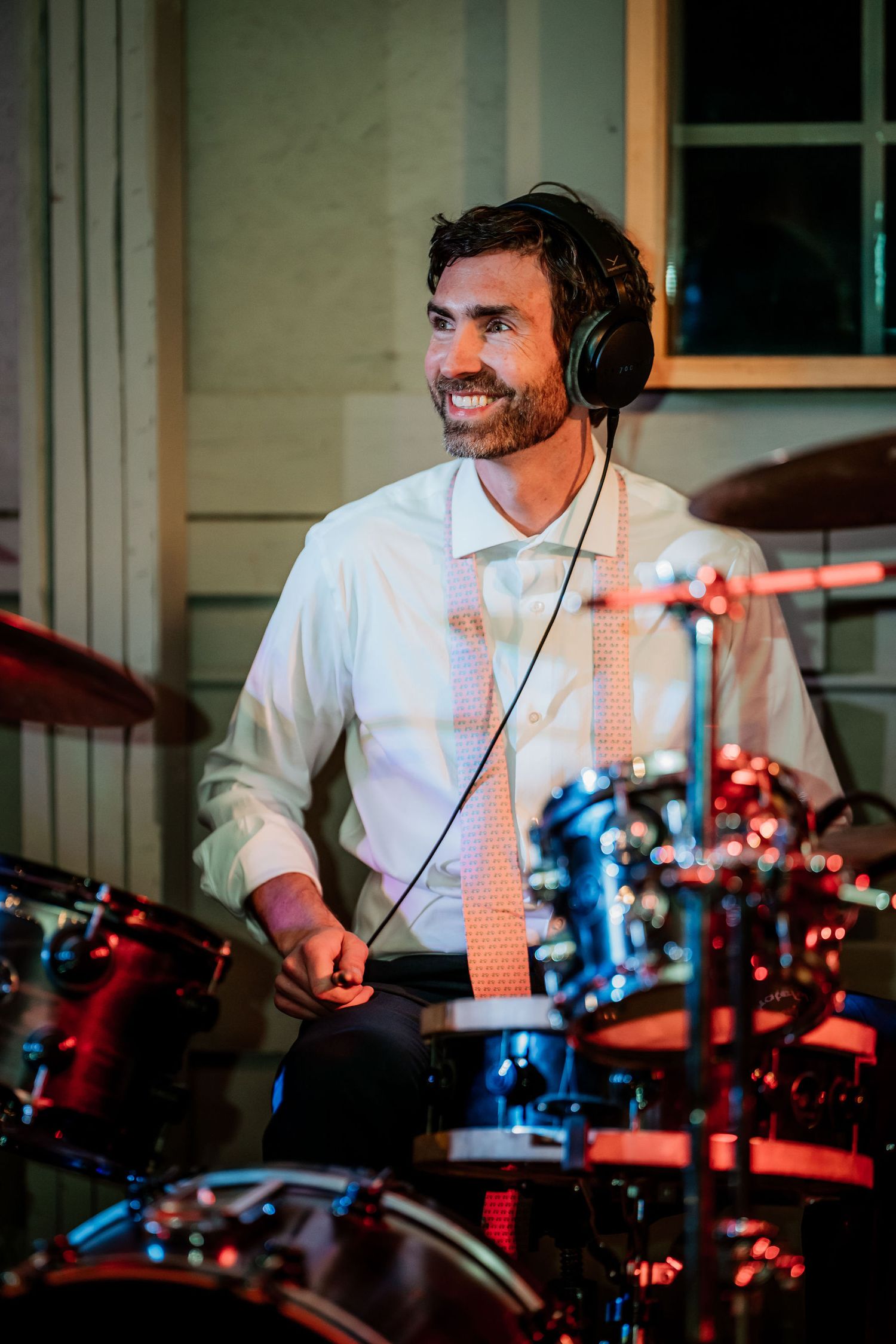 Drummer performing at illuminated music station with headphones.