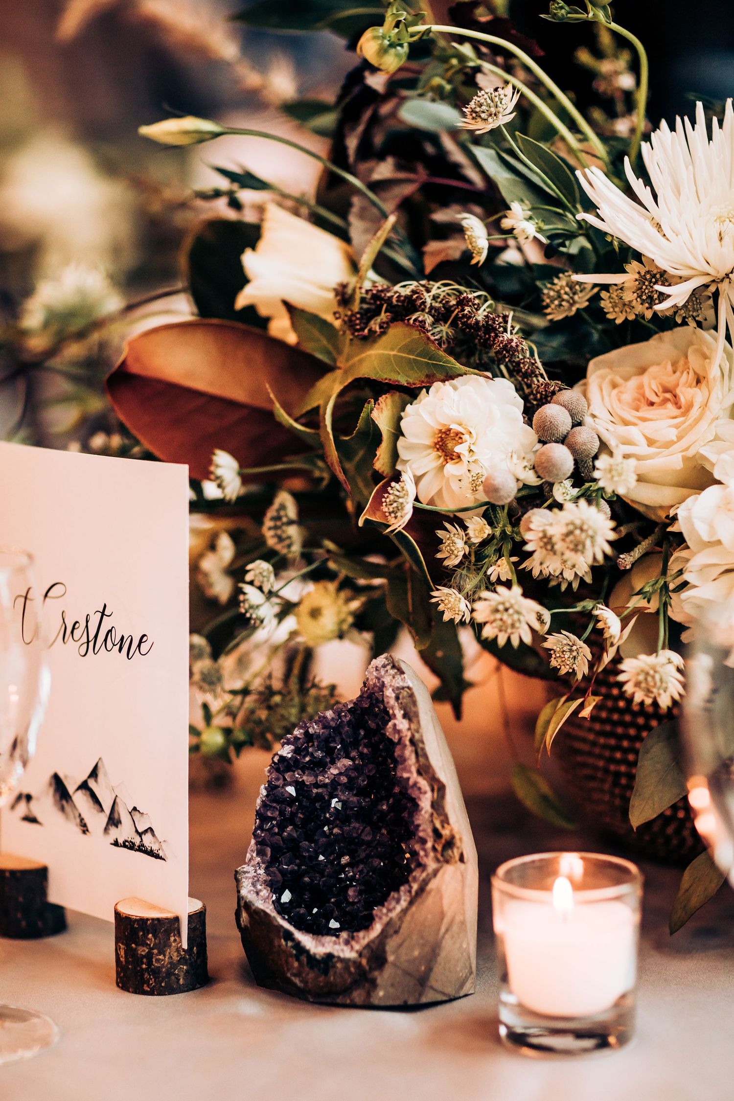 Wedding table decor featuring amethyst crystal, floral arrangements, and candles.