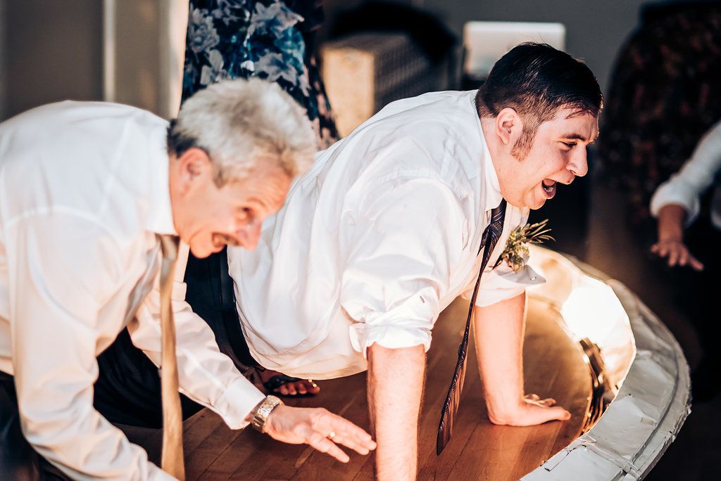 Two people bending down while having fun dancing at a wedding reception.