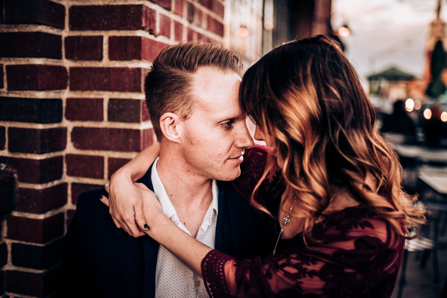 Romantic couple sharing intimate moment against brick wall background.