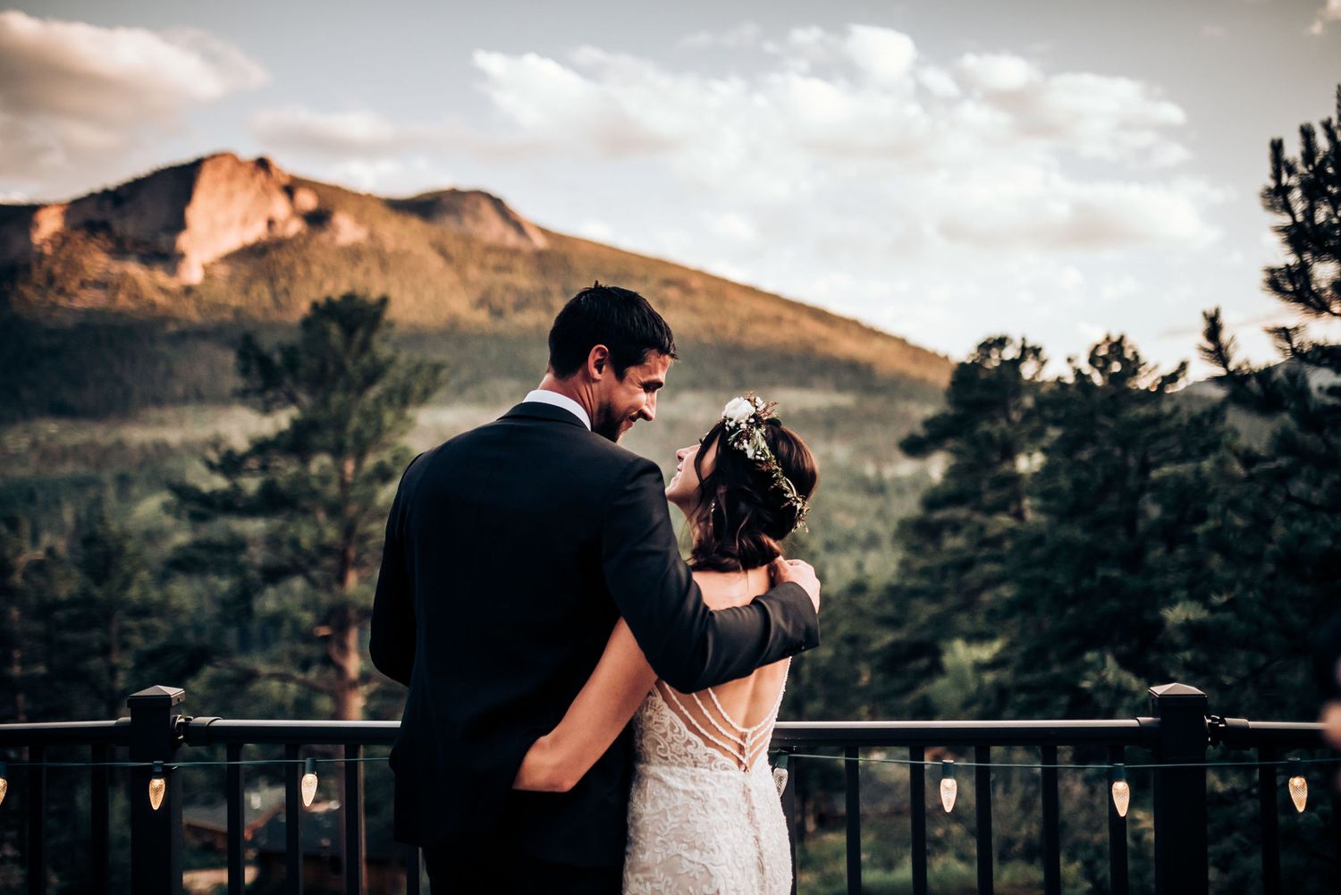 Couple shares intimate moment on balcony with majestic mountain backdrop.
