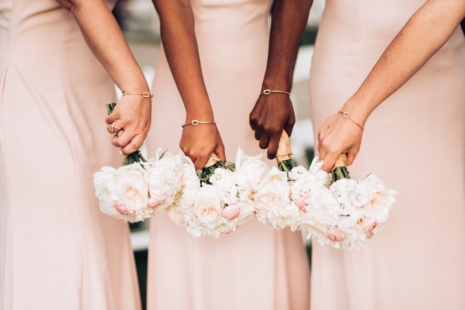 Close-up of bridesmaids holding white and pink bouquets against blush dresses.