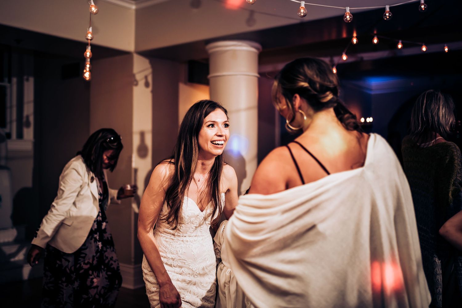 Partygoers enjoying themselves on a dance floor under decorative string lights.