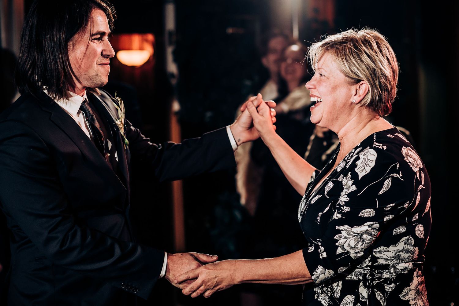 Two people share an energetic dance moment under dim lighting at an indoor venue.