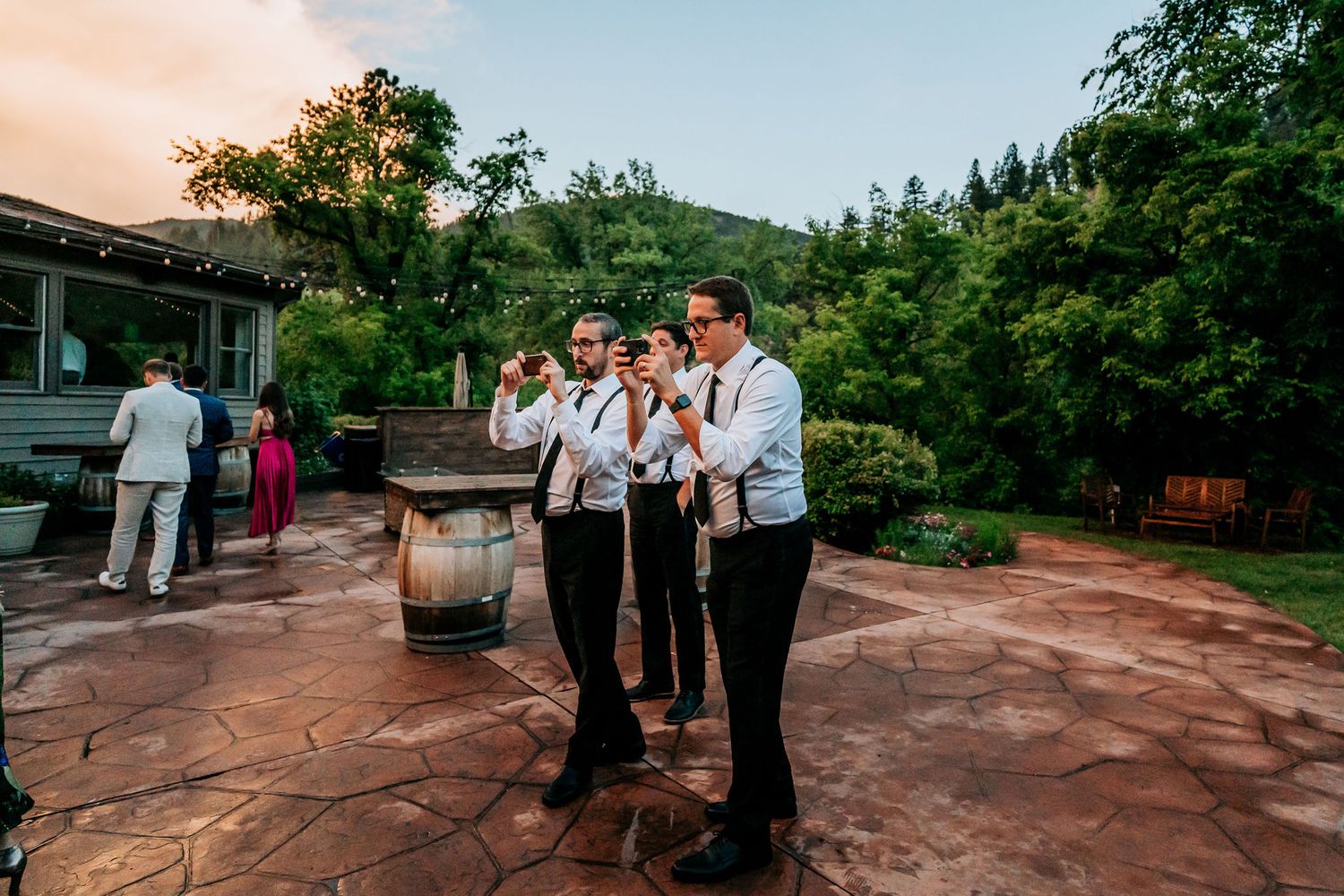 Musicians perform outdoors on a stone patio during sunset at a wedding reception.