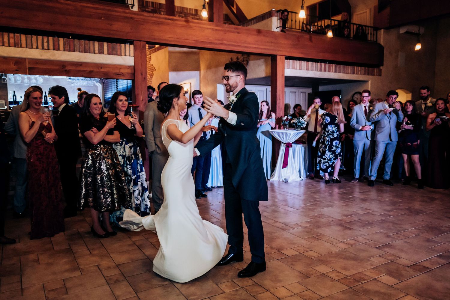 A couple shares their first dance at a wedding reception as guests watch from the dance floor.