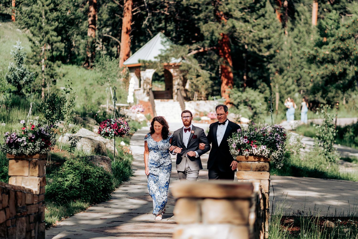 Wedding party members celebrating while running down an outdoor stone walkway.