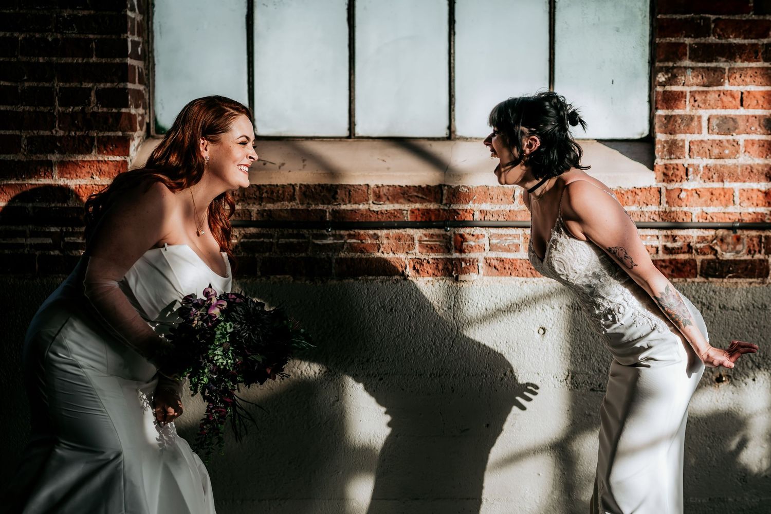 Artistic window light portraits against industrial brick wall background.