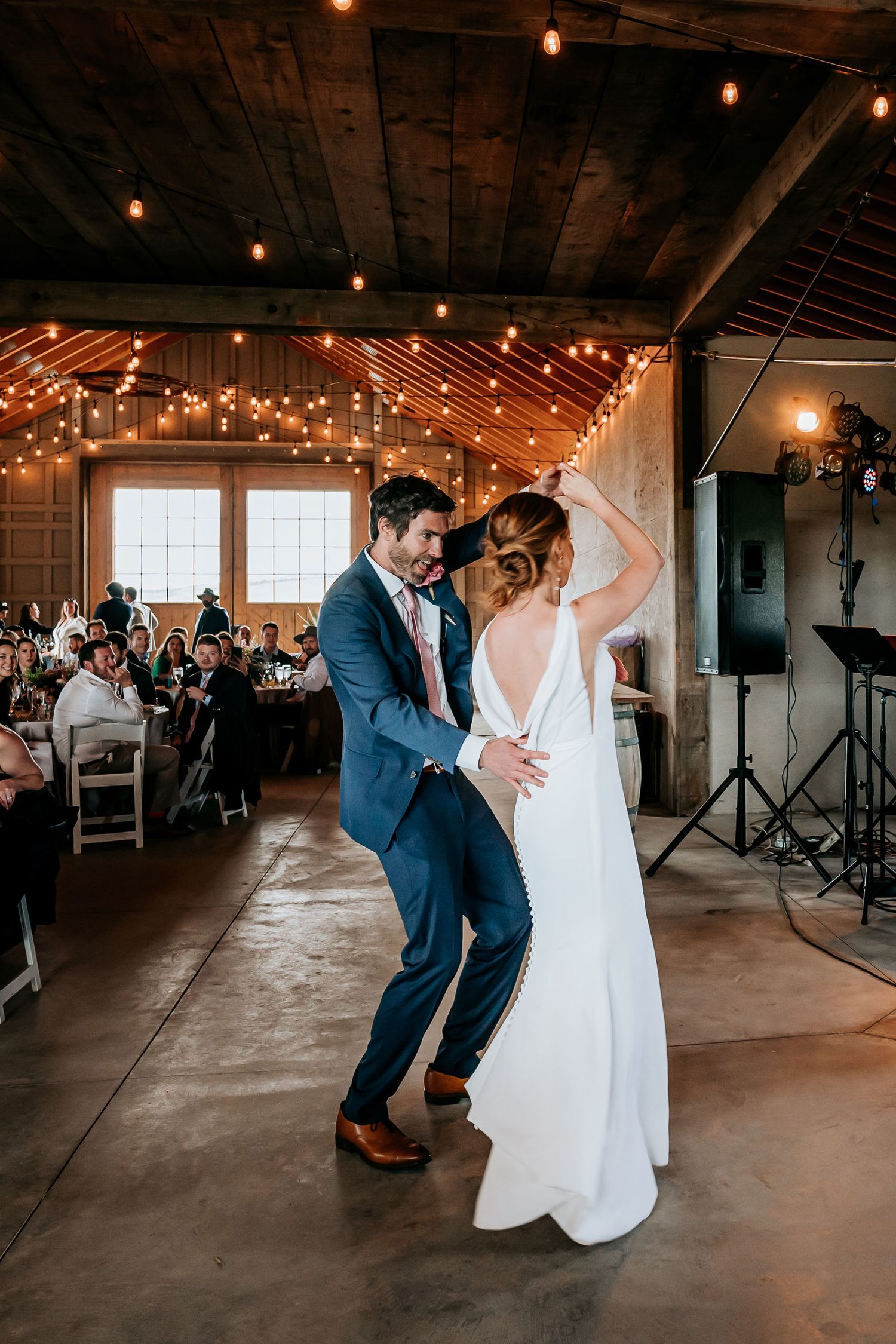 Couple shares a romantic dance moment under twinkling lights at their wedding reception.