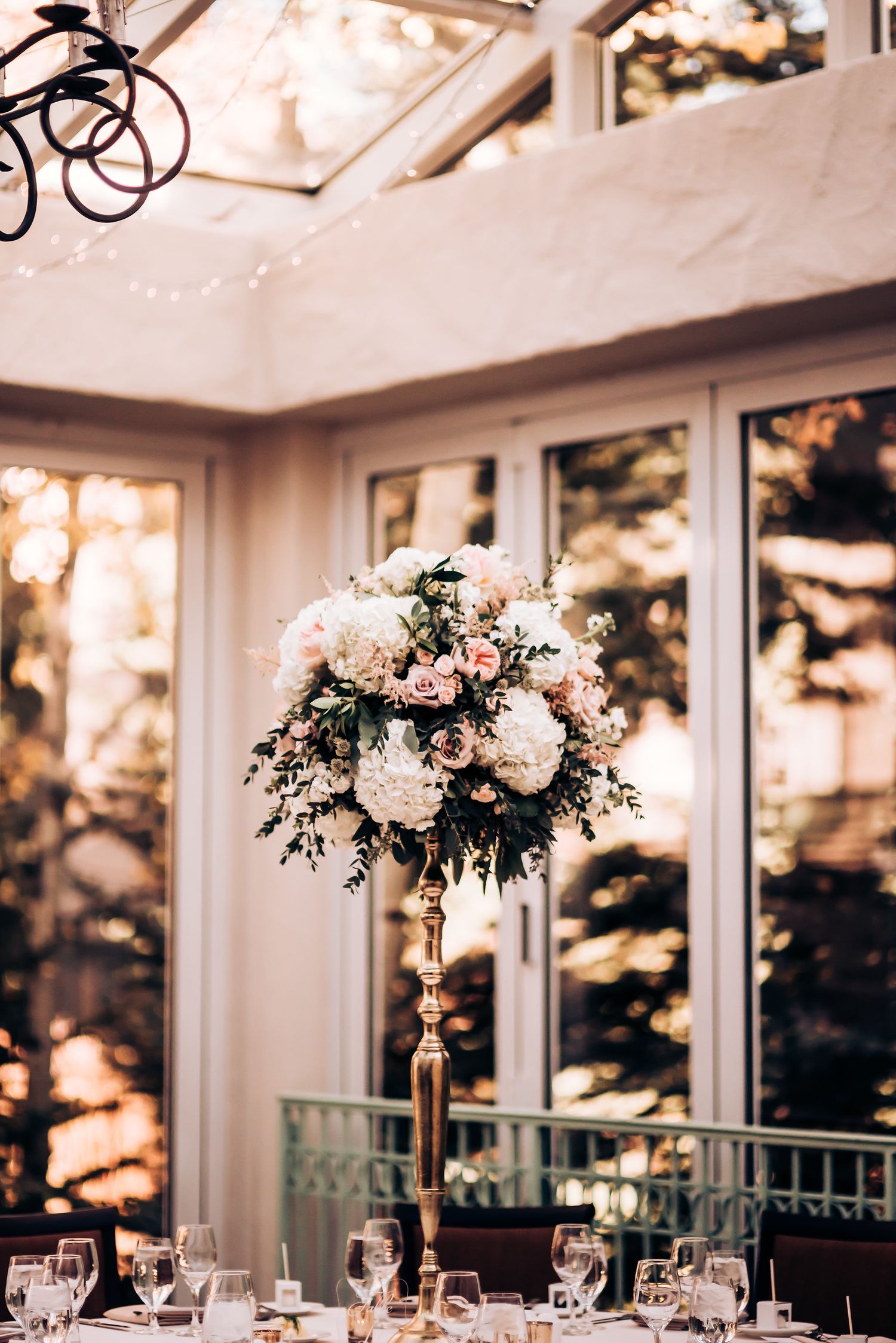 Luxurious floral centerpiece arrangement in white and pink atop a wedding reception table.