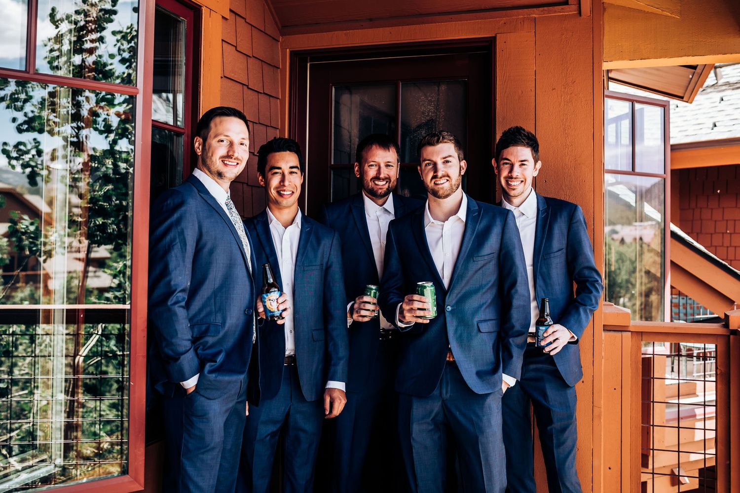 Group in matching navy suits drinking beverages together on an outdoor deck.