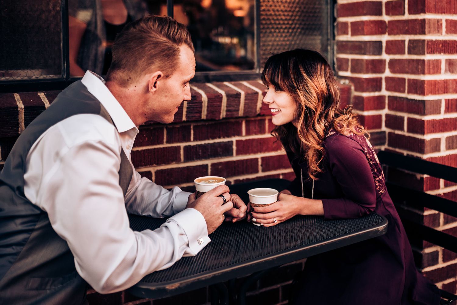 Couple enjoying coffee date at rustic brick cafe.