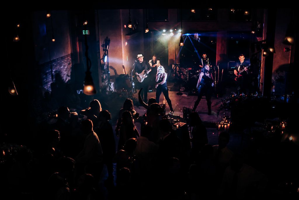 Dark and moody concert-style performance with band playing on stage at wedding reception.