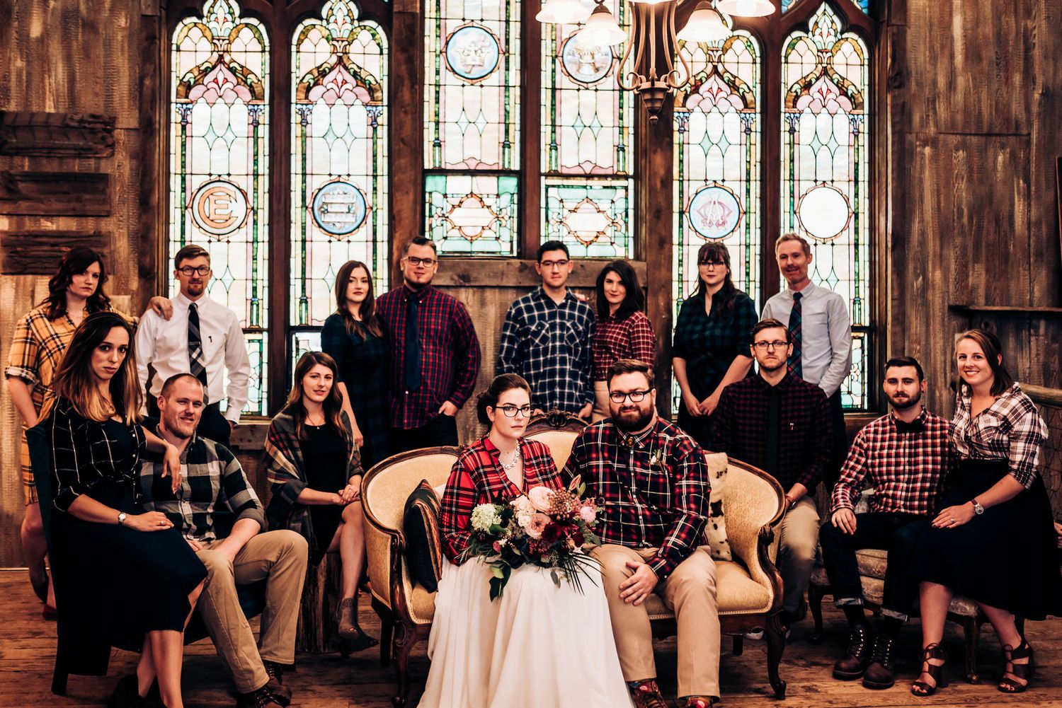 Wedding party group photo inside a church with beautiful stained glass windows and gothic architecture.