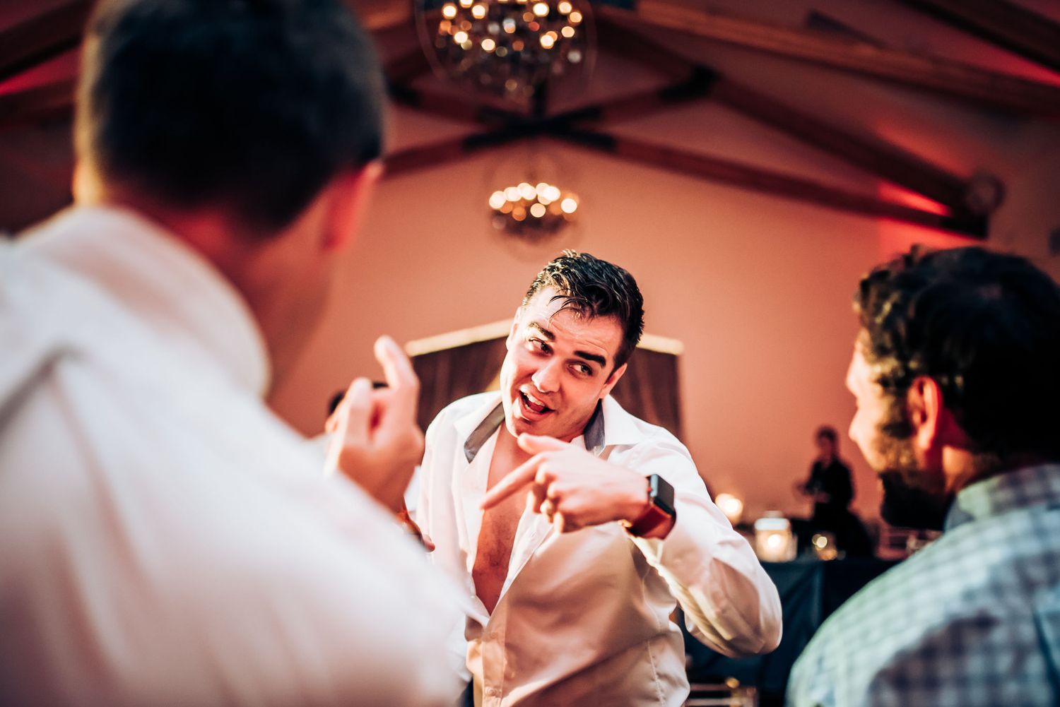Energetic wedding reception moment with attendees engaged in animated conversation.